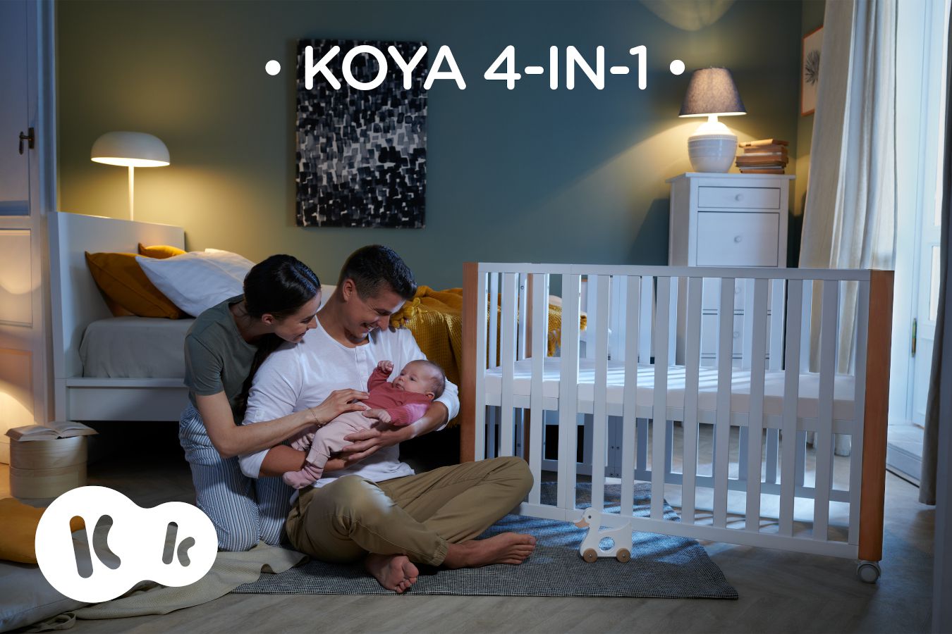 Die Eltern sitzen zu Hause bei ihrem Kind am KOYA-Babybett Text: KOYA 4IN1.